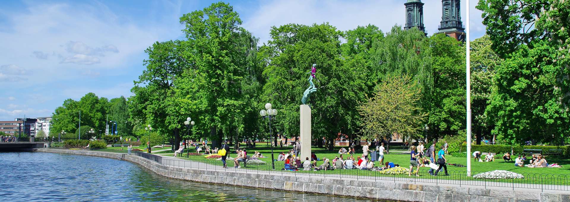 Eskilstuna city park during the summer. People sitting on the grass in a green park.