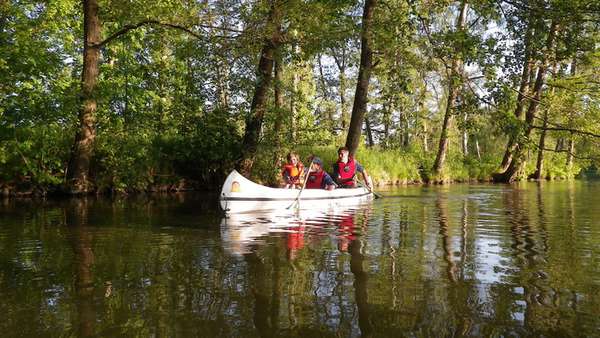 Tre personer som sitter i en kanot. De bär alla röda flytvästar.