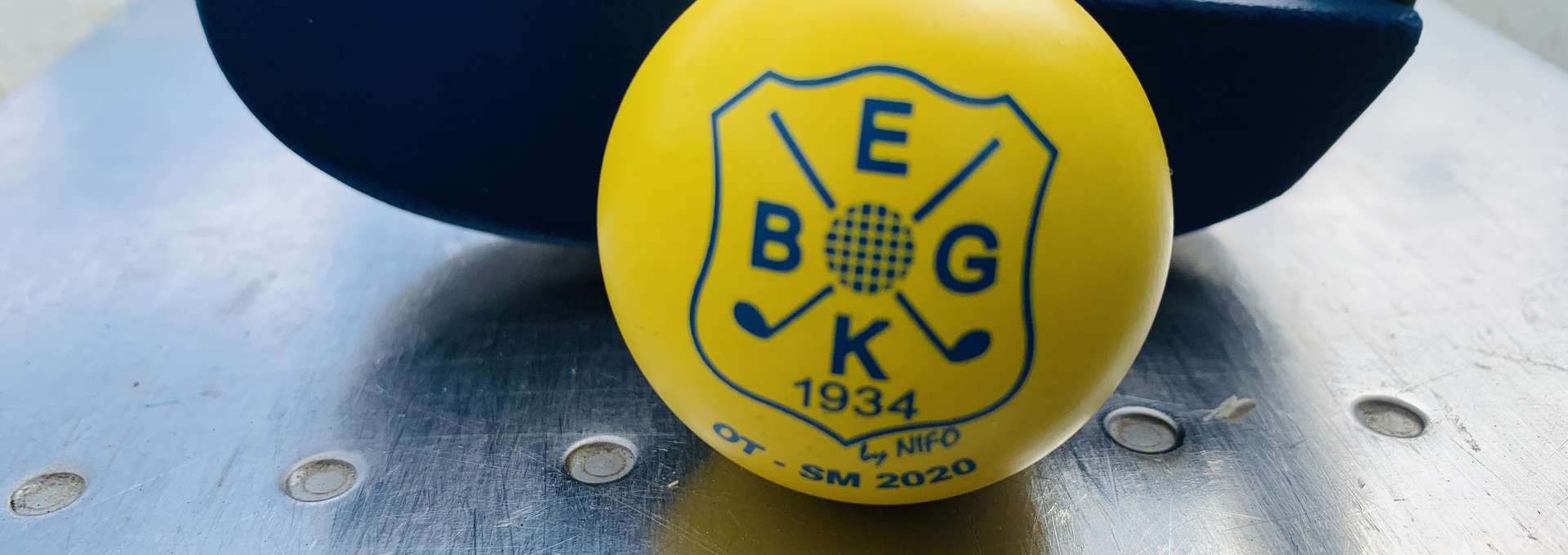 En gul bangolfboll framför en bangolfklubba