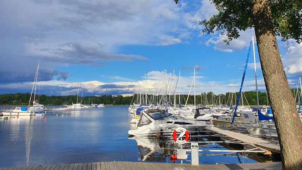 Vy över Sundbyholms Gästhamn. En lång brygga omgärdad av flera båtar.